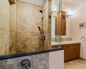 Salle de bain rénovée, muret de céramique et panneau de verre séparant la douche du bain
